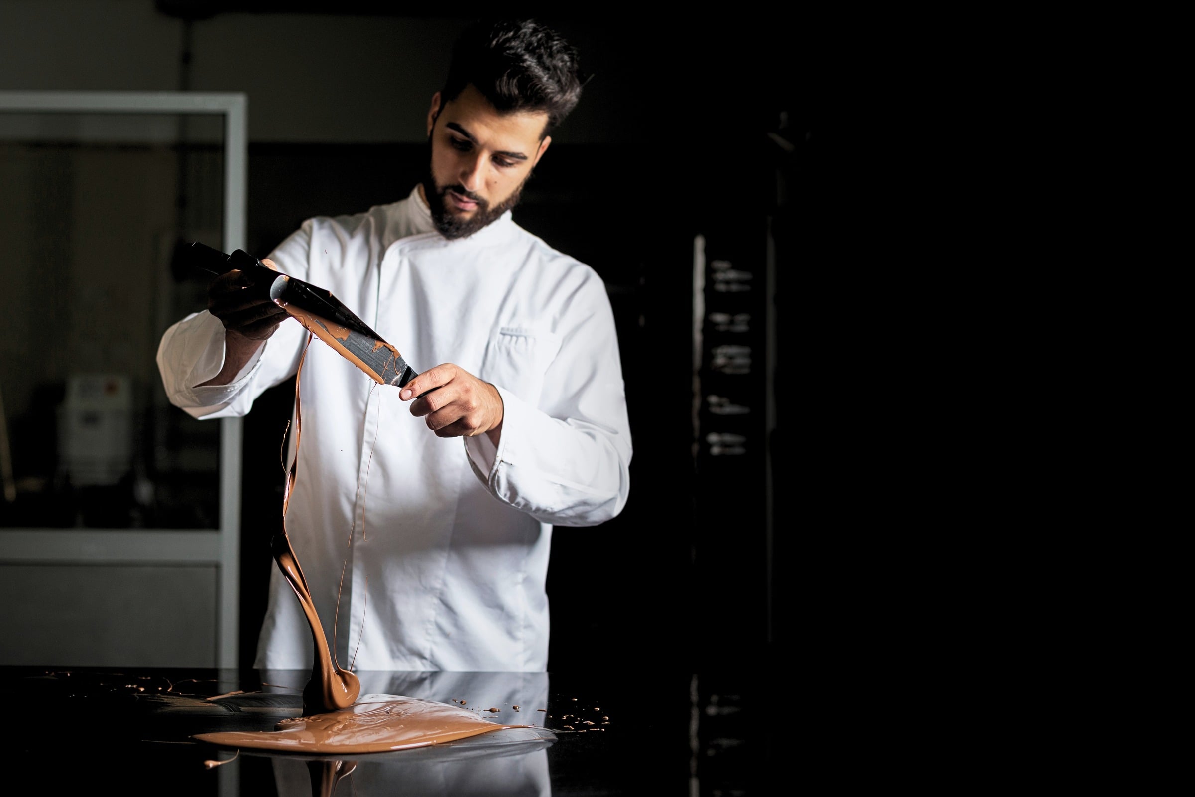 Un pasticcere spatola il cioccolato fuso