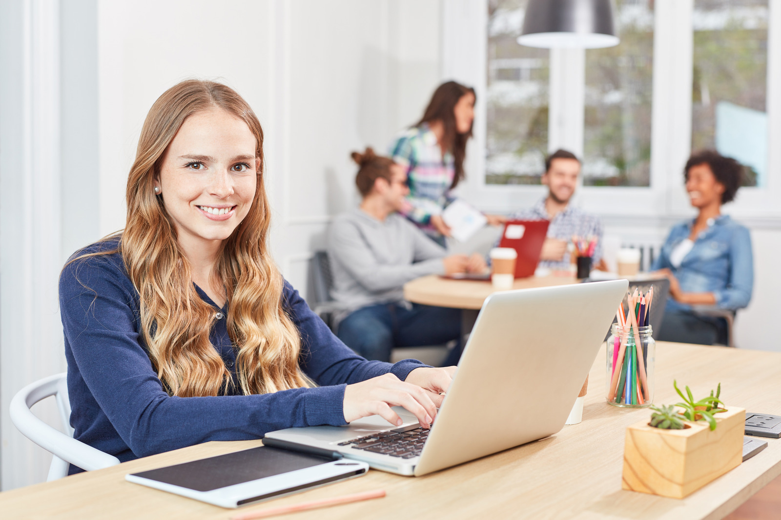 Una ragazza sorridente al computer in un ambiente di lavoro
